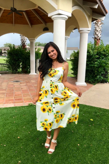 A reviewer showcasing a dress with a lively sunflower print.