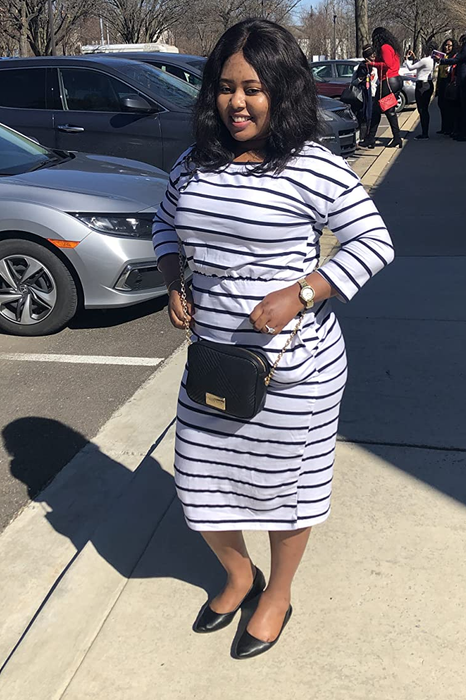 A reviewer wearing a white and black striped midi dress.