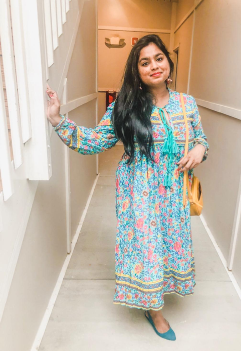 A reviewer in the long-sleeve aqua, yellow, and pink print dress with tassel detailing.