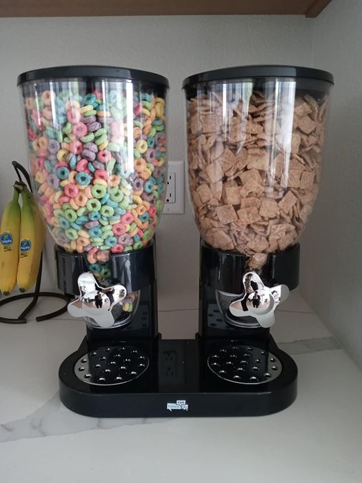 a reviewer's photo of a black cereal dispenser holding two varieties of cereal