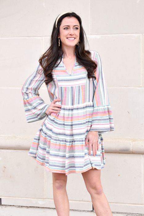 A model in a long-sleeve colorful striped mini dress.