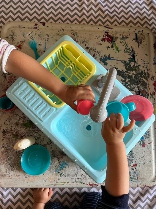 A child playing with toy dishes in a water sensory bin