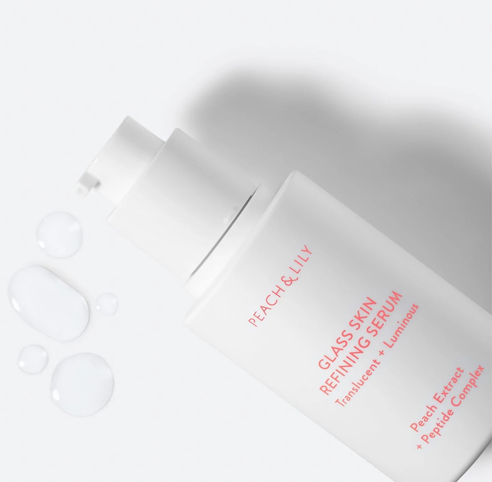The sleek white bottle of serum with pink text, accompanied by a few drops of the clear serum