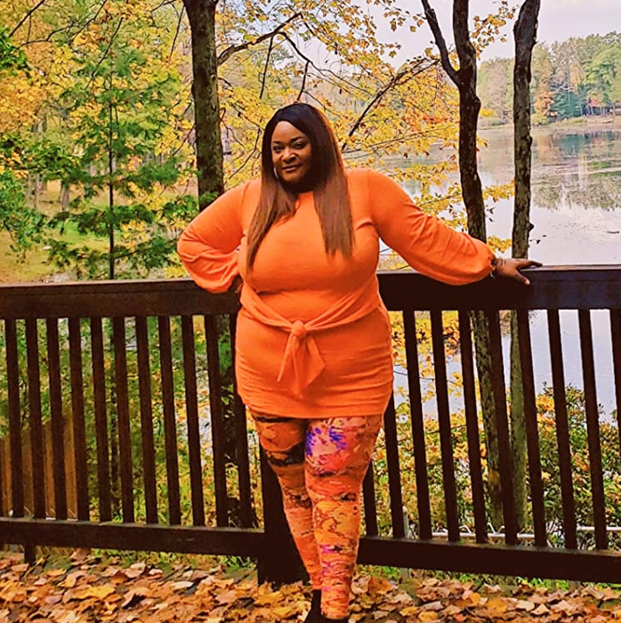 reviewer posing in the orange dress surrounded by autumn leaves