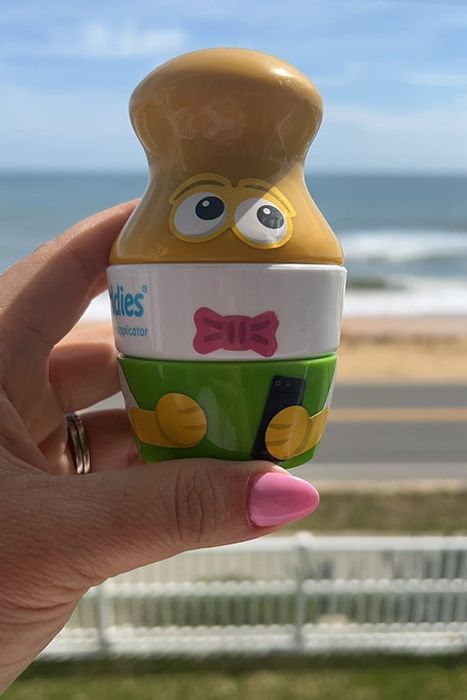 A hand holding the sunscreen applicator, ready for use.