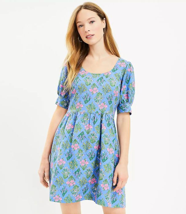 Model in a blue short-sleeve dress with a vibrant floral print in pink, green, yellow, and white