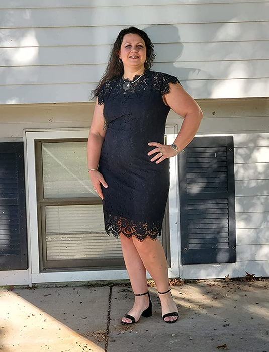 A reviewer models the product in black, teamed with black open-toed heels, posing in front of a white house.