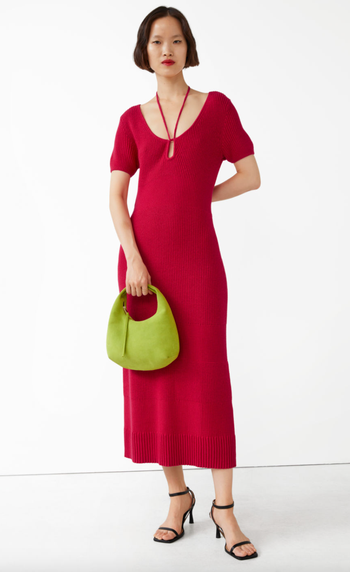 model wearing a red knit midi dress, holding a green bag