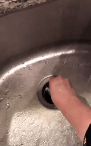 a reviewer’s hand placing the cleaning packet into the sink’s garbage disposal
