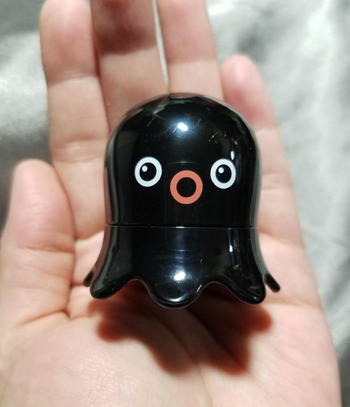 A small black octopus-shaped scrubber held in a reviewer's hand