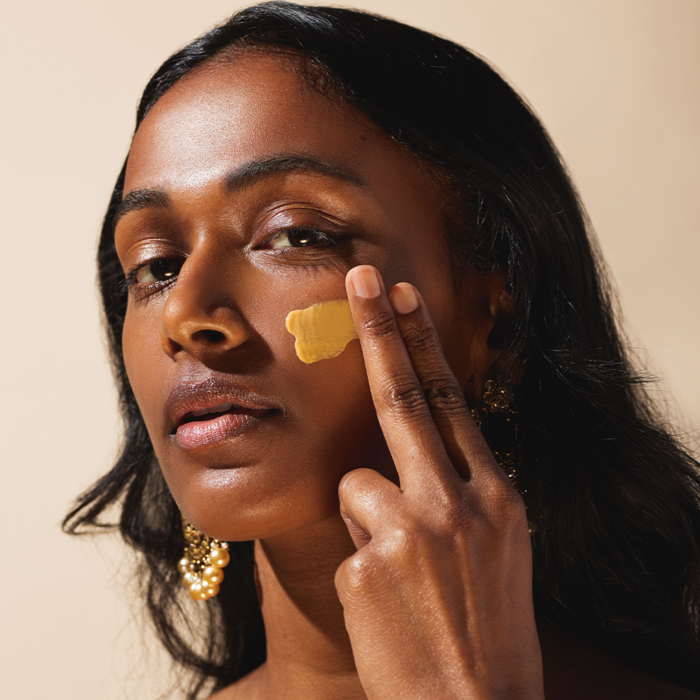 A South Asian model applying the sunscreen on her skin