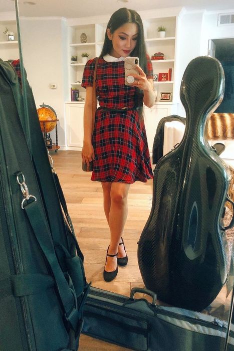A reviewer trying on a red plaid dress that hits just above the knee.