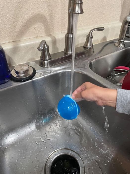 A person refilling a reusable water balloon at the sink