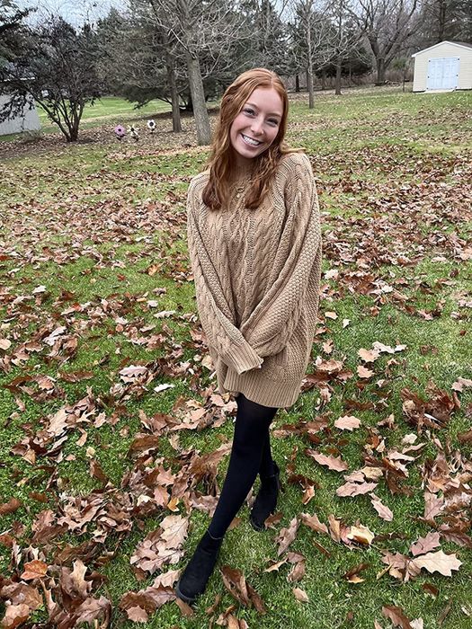 reviewer image wearing the brown sweater dress surrounded by autumn leaves