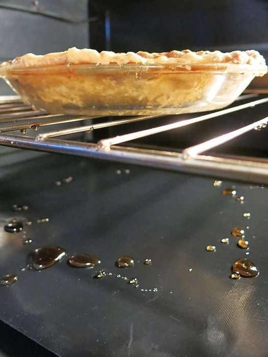 An oven liner coated with residue at the bottom of an oven