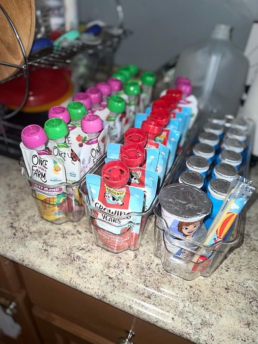 A variety of children’s juice bottles and squeezable food pouches arranged on a kitchen counter