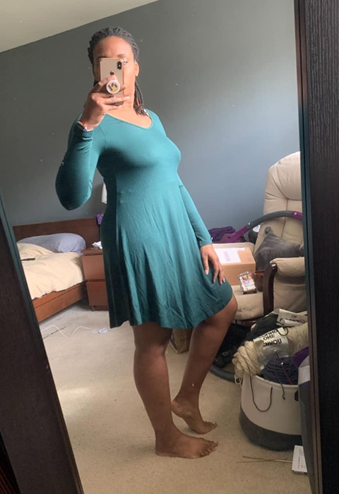 Reviewer in a teal scoop neck dress with an asymmetric hem.