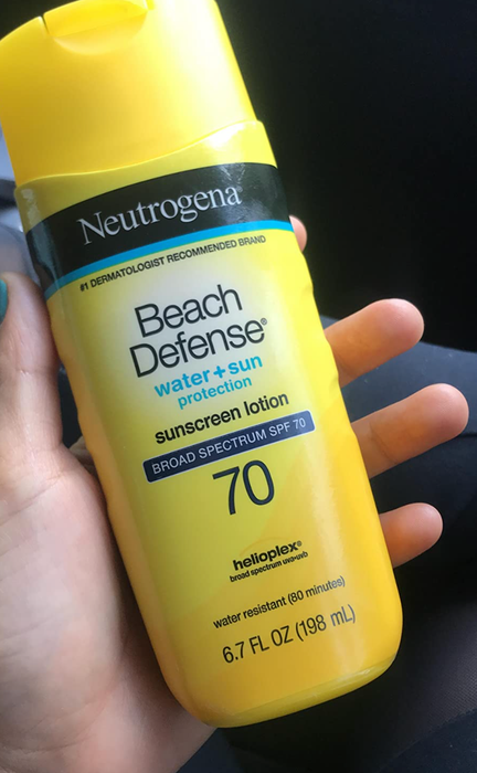 The reviewer holding a bottle of sunscreen.