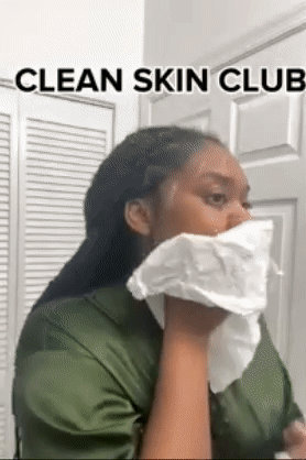 A reviewer using a white towel to cleanse their face.