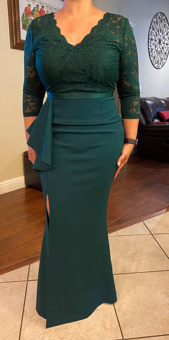 Reviewer showing off the dress in dark green on a tiled floor.