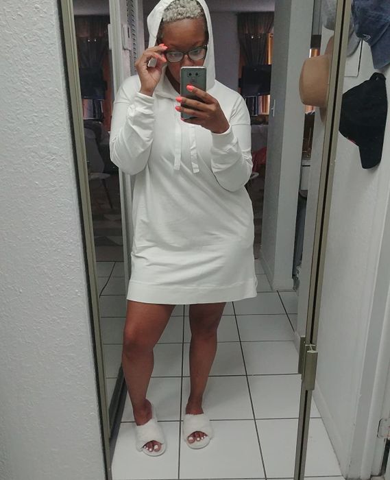 Reviewer rocking a white, above-the-knee, long-sleeve hoodie dress with the hood up