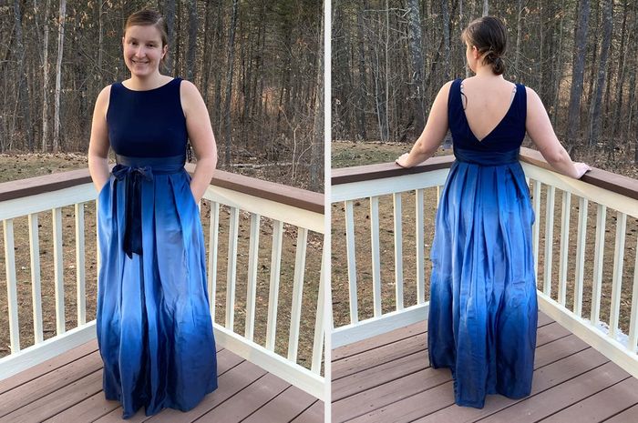 A reviewer showcases both the front and back views of a navy blue high-neck, backless sleeveless dress with a matching bow around the bodice, paired with an ombre blue skirt, while standing on a wooden porch.