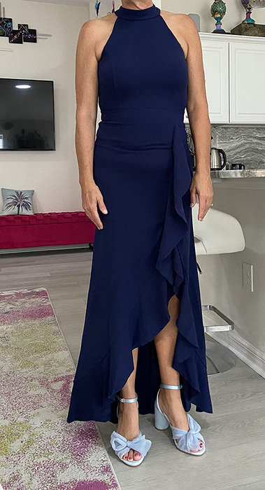 The reviewer is showcasing the dress in navy blue, paired with light blue bow heels, standing on a hardwood floor.