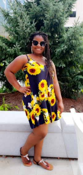 A reviewer wearing a black spaghetti-strap dress.