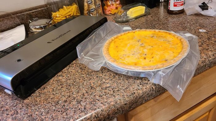 A vacuum-sealed quiche placed on a kitchen countertop alongside a vacuum sealer, showcasing efficient food storage for meal planning