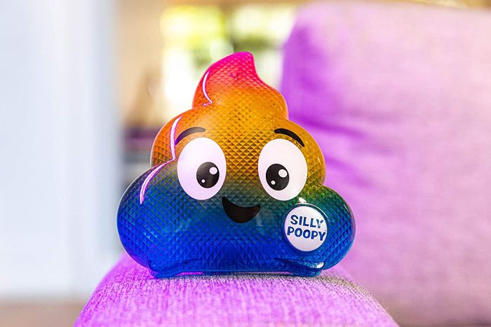 The rainbow poop emoji, complete with a smile, sits on a chair.