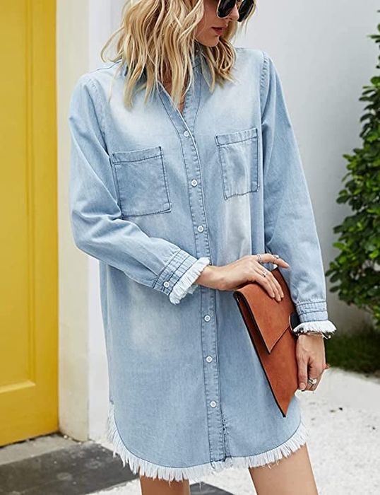 A model in a long-sleeved mini dress with frayed cuffs in a light wash denim.