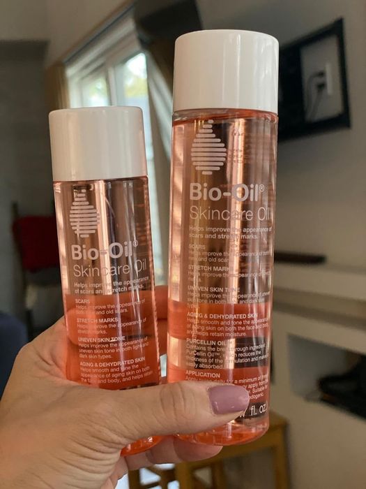 A reviewer is seen holding two bottles of Bio-Oil.