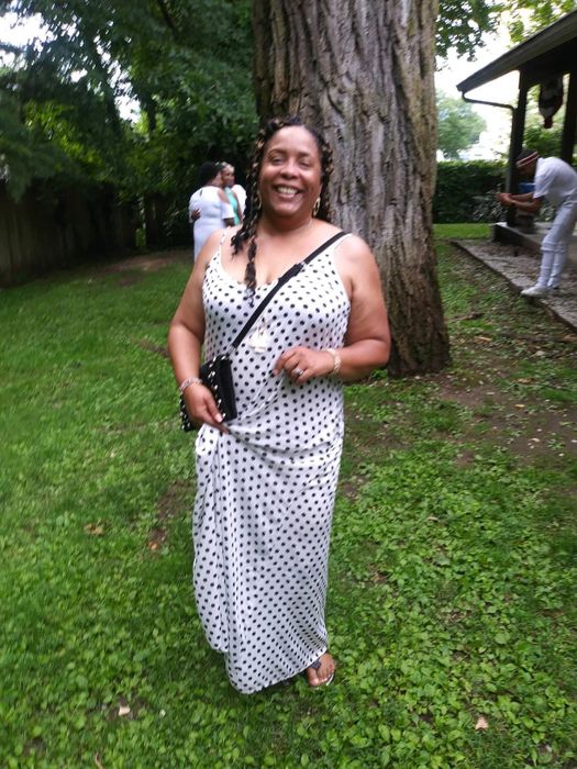 Reviewer wearing a white spaghetti strap dress adorned with black polka dots.