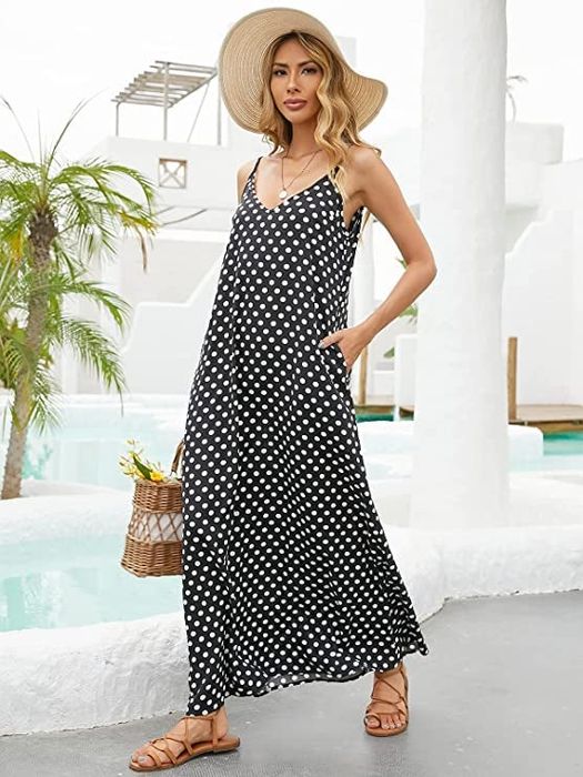 Model in a black dress with white polka dots, casually keeping one hand in a pocket.