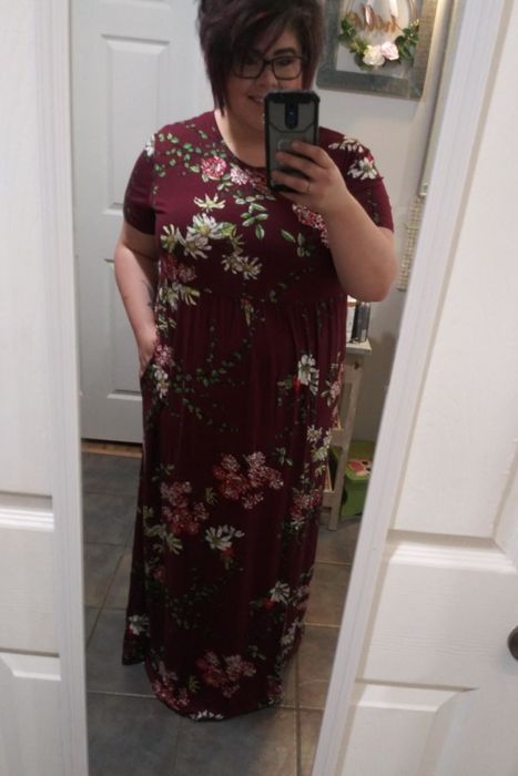 A reviewer showcasing a short-sleeve dress in a burgundy floral print.