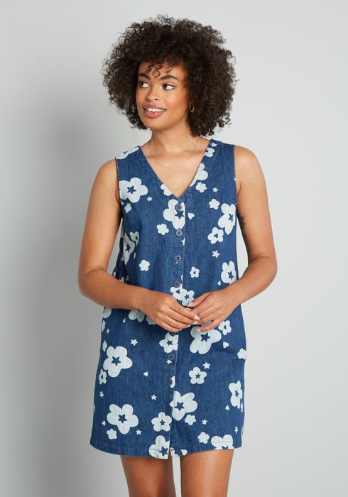 A model wearing a dark wash denim button-down jumper with white graphic flowers.