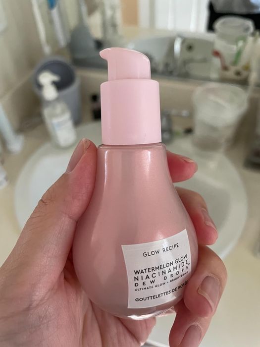 A reviewer is holding the bottle of serum in their hand.