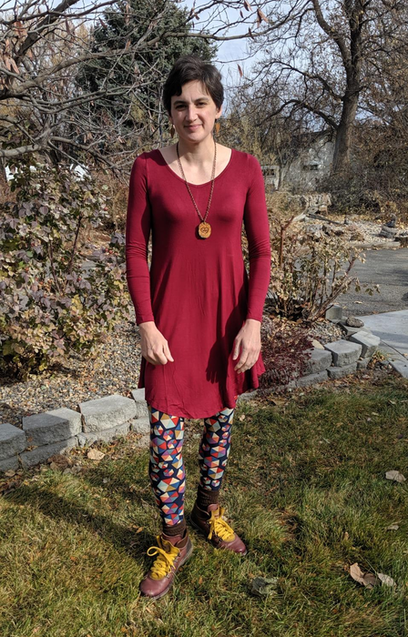 A reviewer showcasing a dark red outfit paired with leggings.