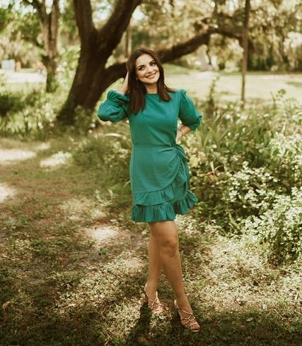reviewer image wearing the green dress, posing outdoors
