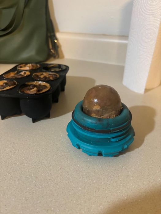 A blue treat-dispensing pet toy with frozen treats resting on a kitchen countertop