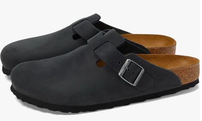A pair of black slip-on clogs featuring a buckle strap and cork soles, set against a white backdrop