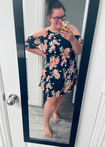 reviewer modeling the dress in navy with a pink floral design
