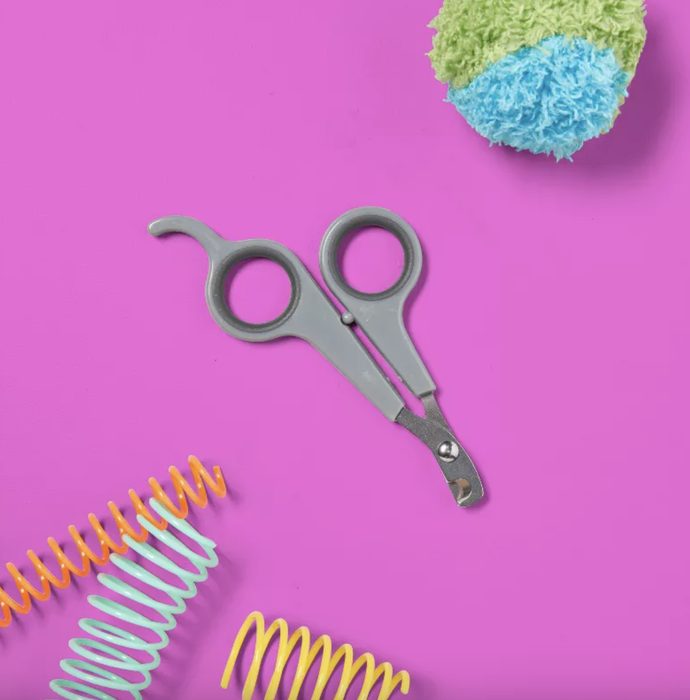 Pet nail clippers set against a vibrant pink background with colorful spiral toys, perfect for grooming and pet care shopping.
