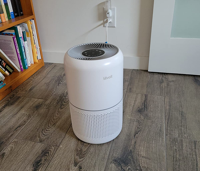 reviewer image of the sleek white air purifier placed on a wooden floor