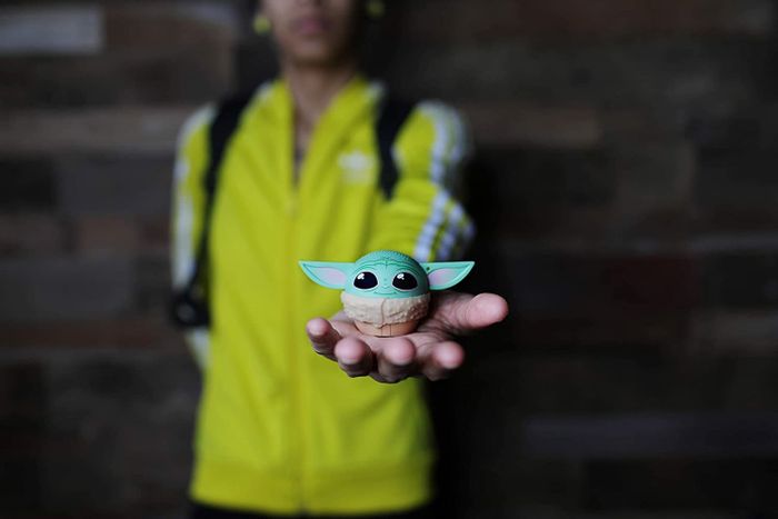 A model holding the round, ear-adorned speaker in the palm of their hand