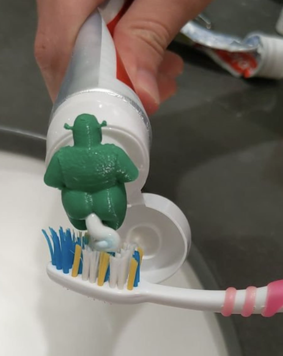 a still image of the 3D-printed green ogre with toothpaste emerging from its backside