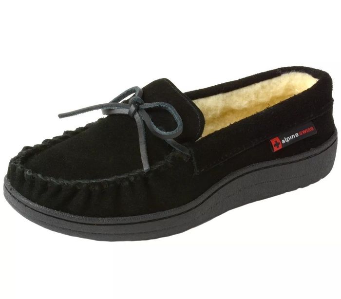 Black moccasin-style slippers by Alpine Swiss, featuring a decorative bow on top and a cushioned interior for added comfort.
