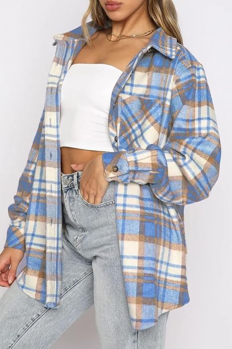 Model styling a plaid shirt layered over a white tube top and light-wash jeans