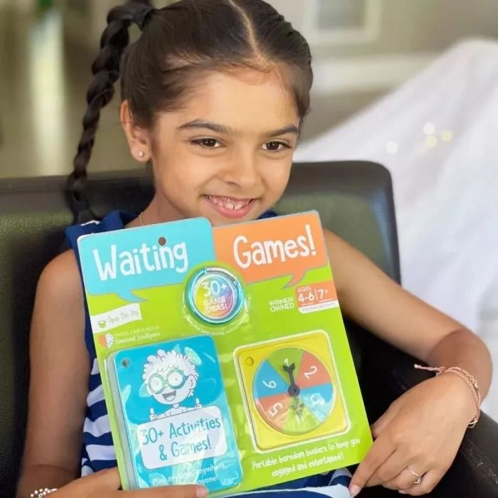 A young girl holding an activity book titled 'Waiting Games,' featuring over 30 exercises tailored for ages 4-7