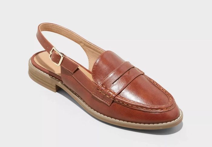 A brown leather slingback loafer with a strap and buckle detail, showcasing a low heel and timeless design.